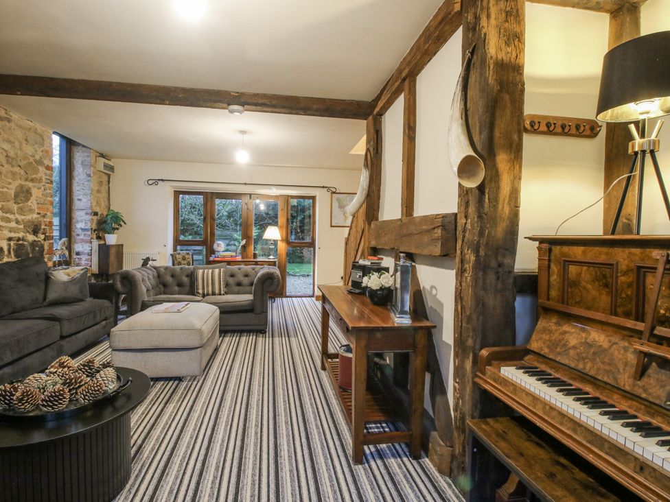 A living room with a sofa, piano, and coffee table at Upper Home Farm near Cardington