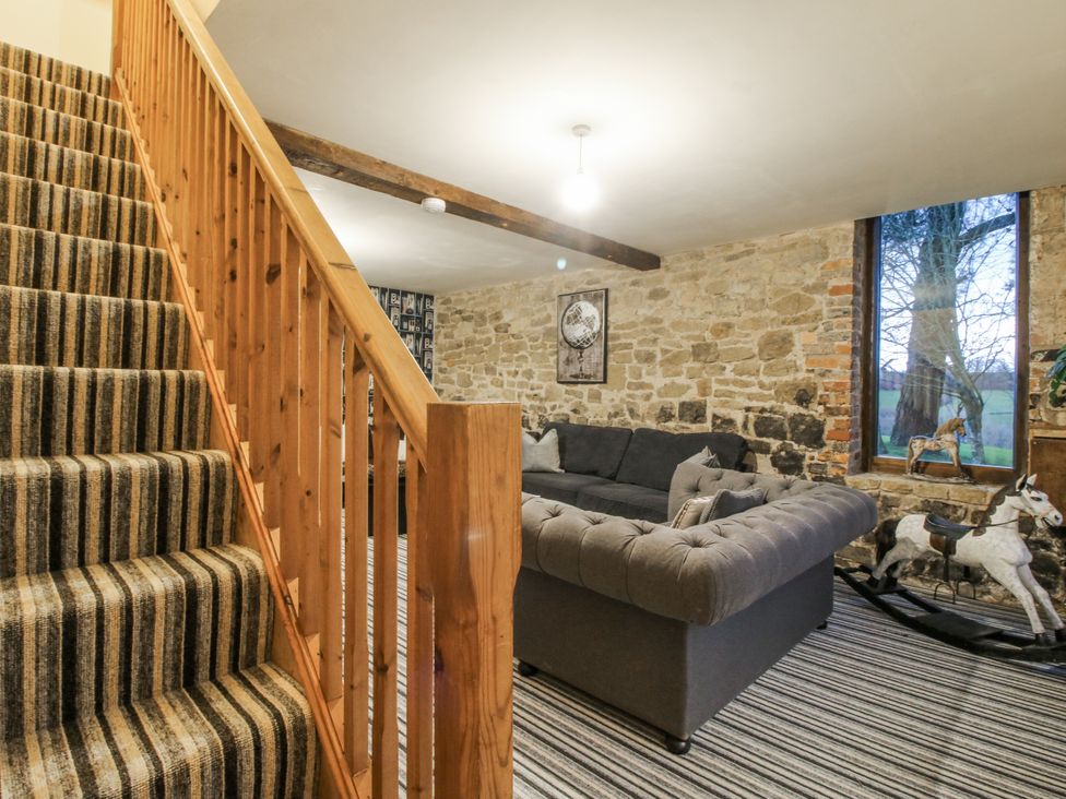 A living room with a sofa and staircase at Upper Home Farm near Cardington