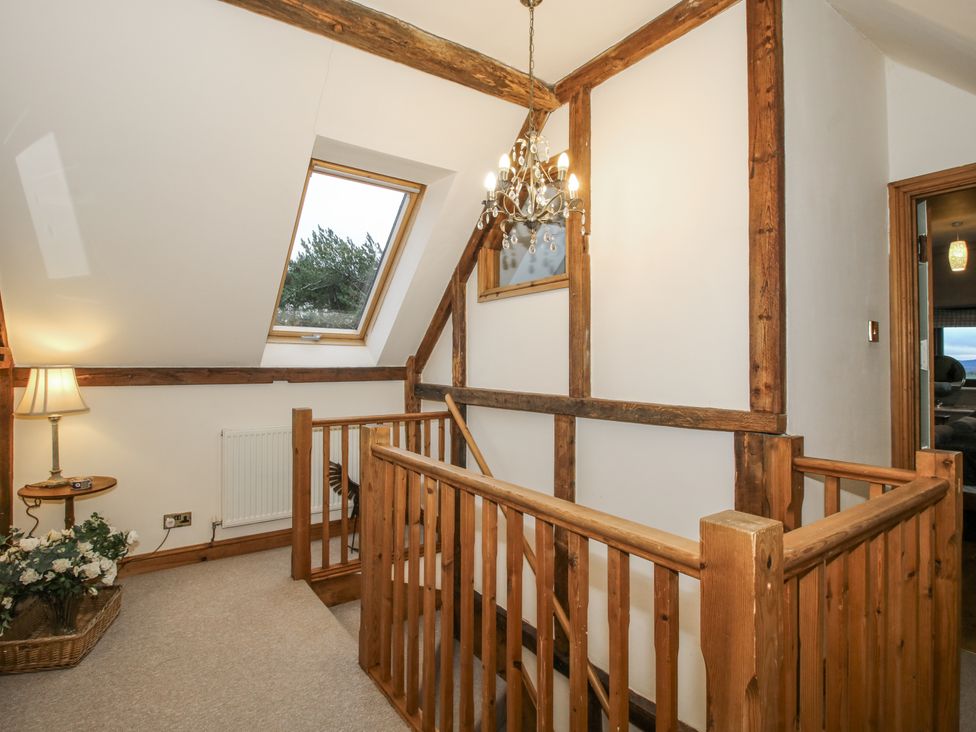 A hallway with a staircase and chandelier at Upper Home Farm near Cardington