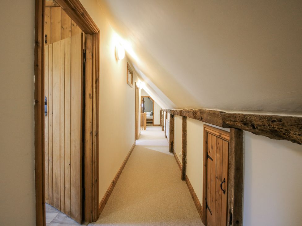 A hallway with wooden beams and doors at Upper Home Farm near Cardington