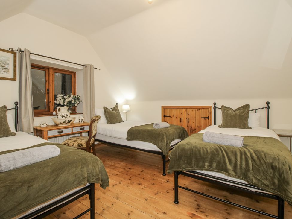 A bedroom with three beds and a window at Upper Home Farm near Cardington