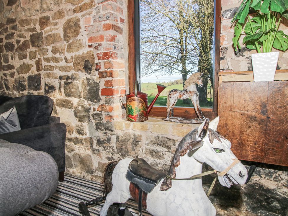 A living room with a stone wall and horse decor at Upper Home Farm near Cardington
