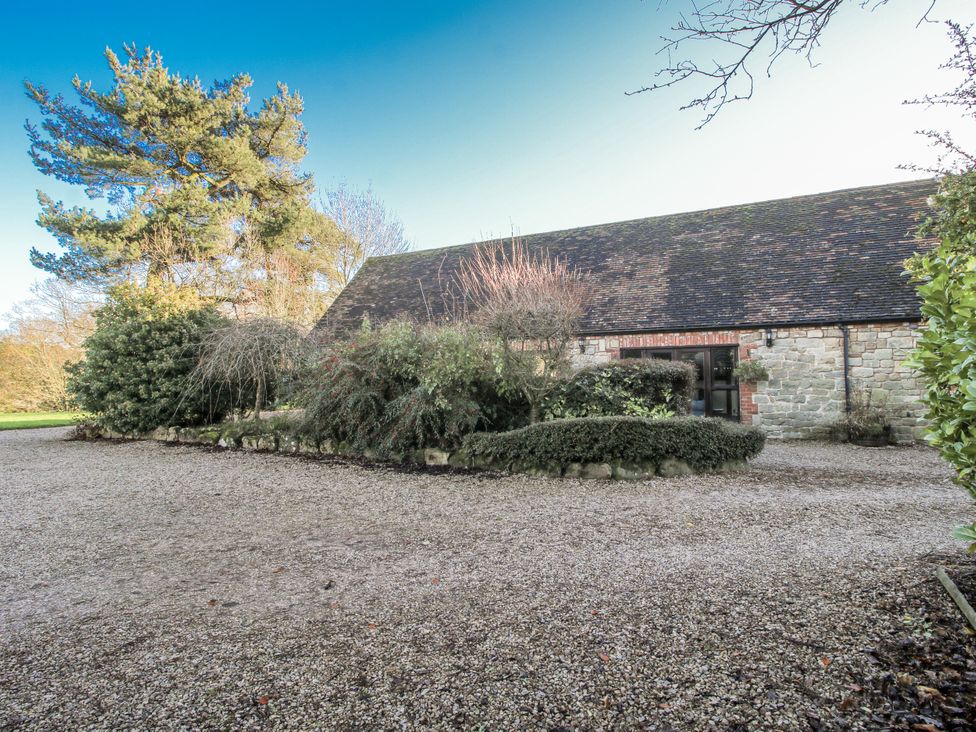 An outdoor view of a gravel area with a building and surrounding greenery at Upper Home Farm near Cardington