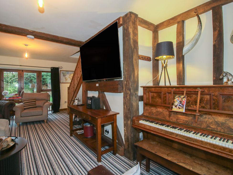 A living room with a piano and TV at Upper Home Farm near Cardington