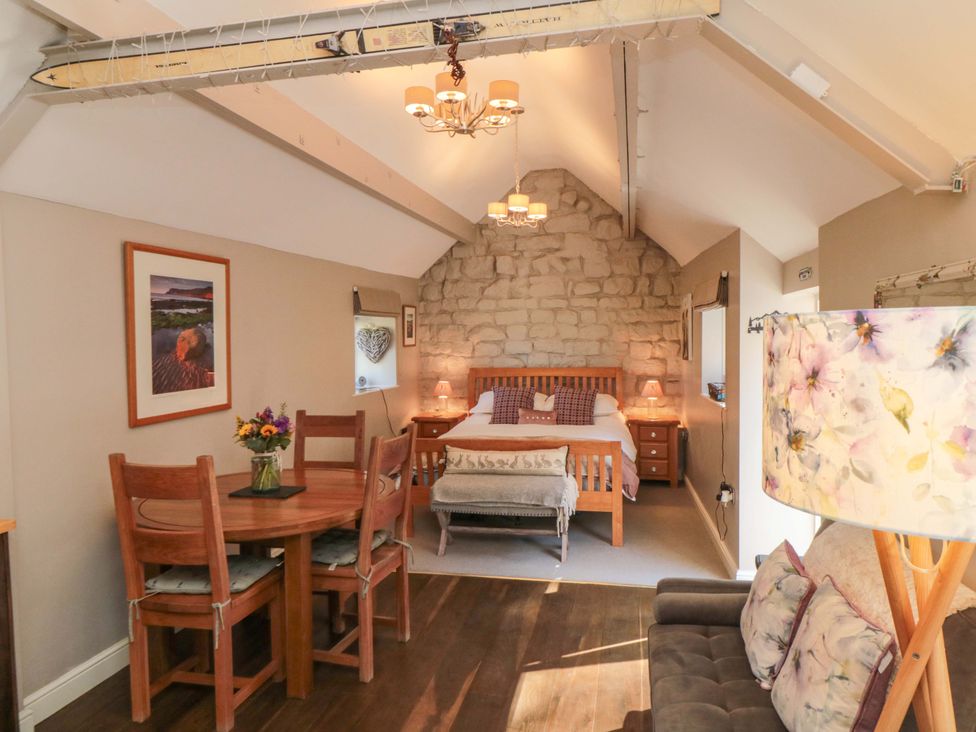 A bedroom with a bed and dining area at Maltkiln House Annexe Chop Gate near Stokesley