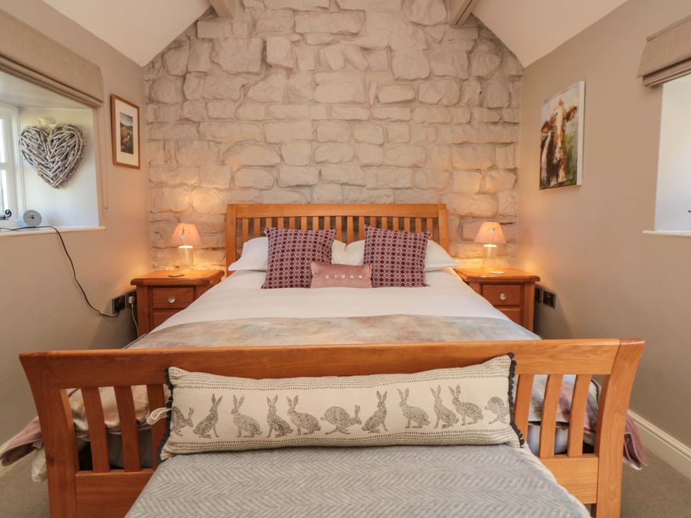 A bedroom with a stone wall and wooden furniture at Maltkiln House Annexe in Chop Gate near Stokesley