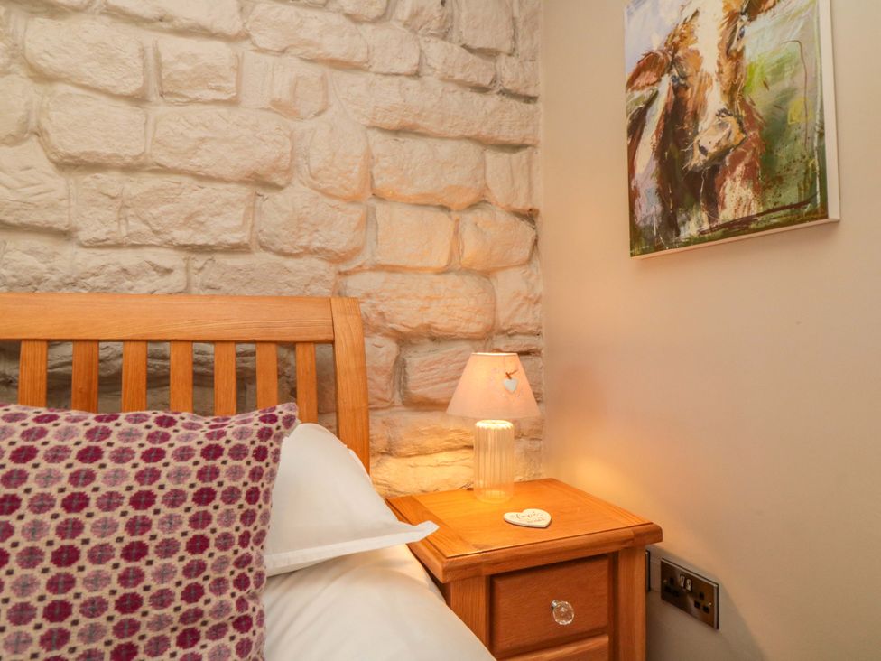 A bedroom with a wooden bed and a nightstand at Maltkiln House Annexe in Chop Gate near Stokesley