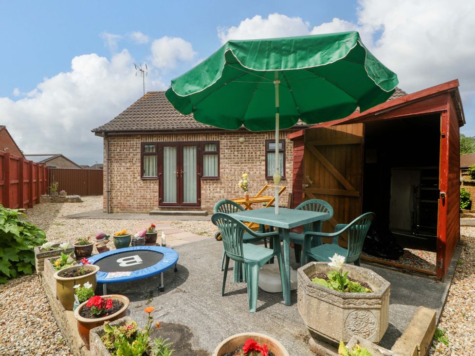 A garden with a table and chairs under an umbrella at Fatima in Burnham-On-Sea