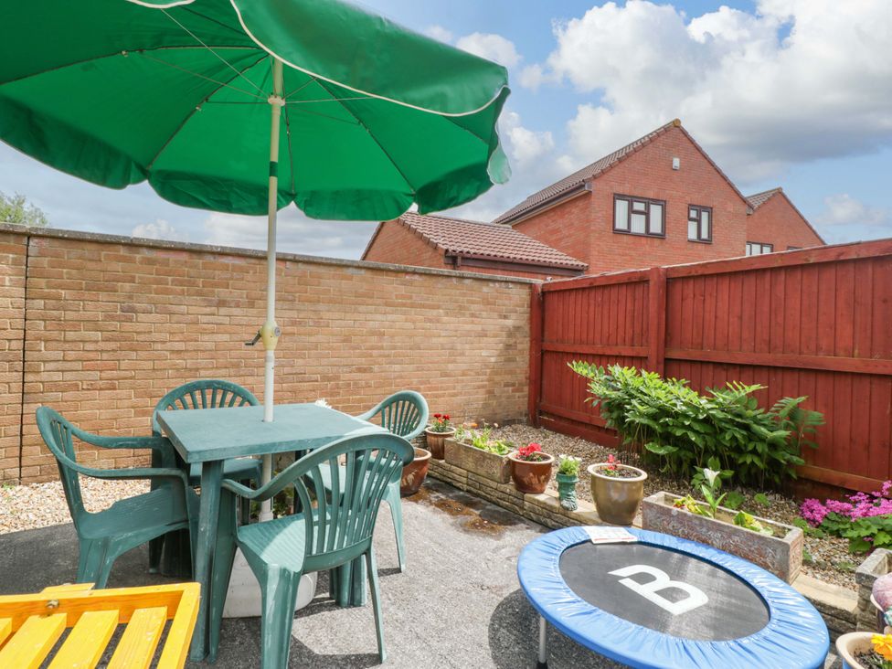A garden with a table and chairs under an umbrella at Fatima in Burnham-On-Sea