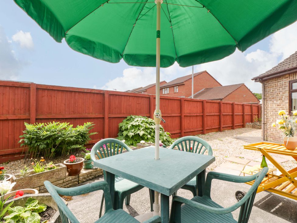 A garden area with a green umbrella and table with chairs at Fatima in Burnham-On-Sea