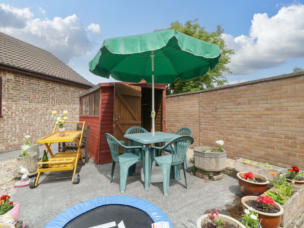 A garden with a table and chairs under an umbrella at Fatima in Burnham-On-Sea