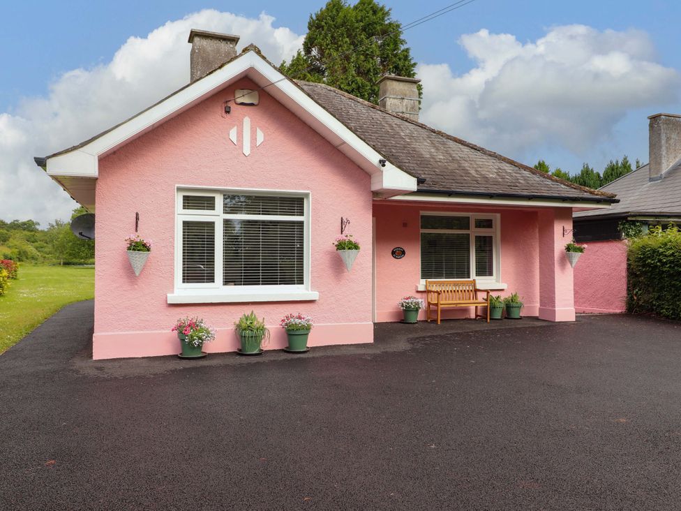 A house with a pink exterior and a bench outside at Rosemont in Adare