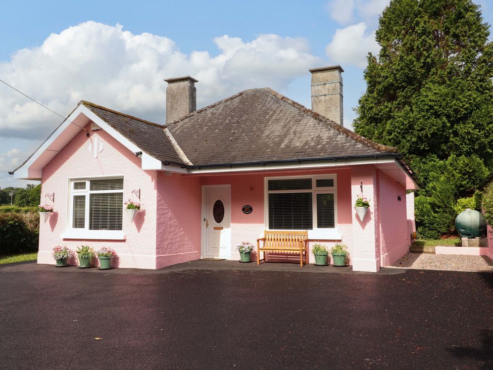 A pink house with a porch and a bench at Rosemont in Adare