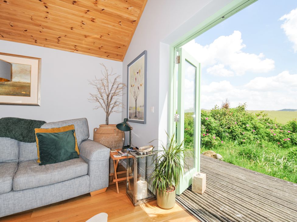 A living room with a sofa and door opening to the outside at Smugglers, Bodmin Moor, St Breward near St Tudy
