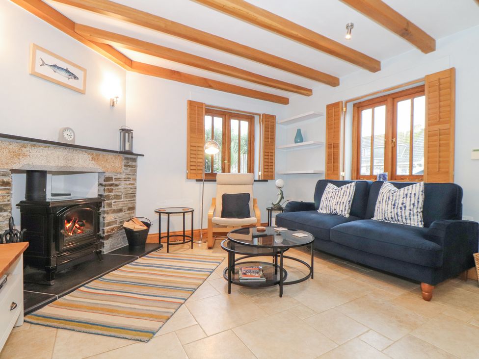 A living room with a fireplace a blue sofa a cream armchair and a round glass coffee table at Splatt Barn in Rock