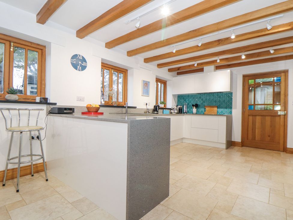 A kitchen with a gray countertop island wooden beams on the ceiling and a wooden door at Splatt Barn in Rock