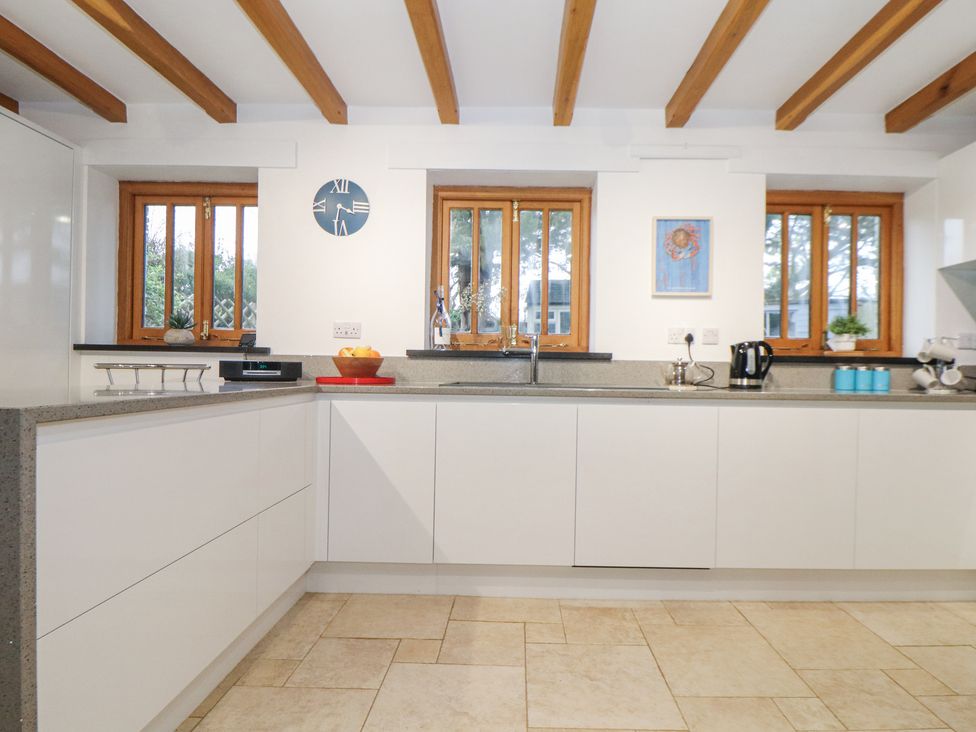 A kitchen with white cabinets wooden window frames and ceiling beams at Splatt Barn in Rock