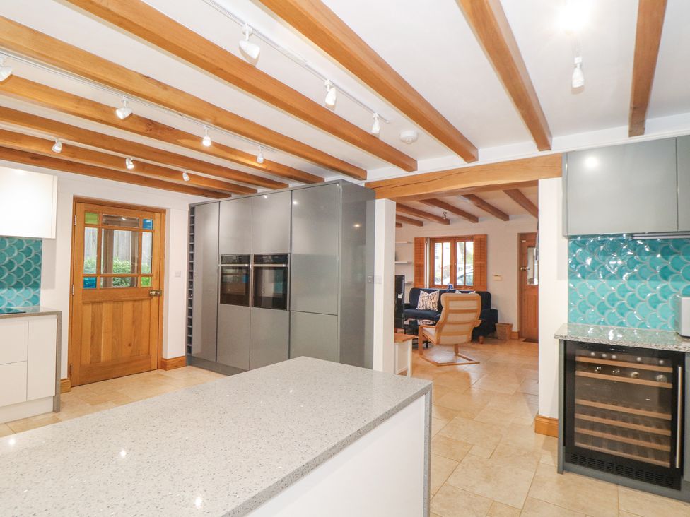 A kitchen with wooden beams a wooden door grey cabinets and a blue tiled backsplash at Splatt Barn in Rock