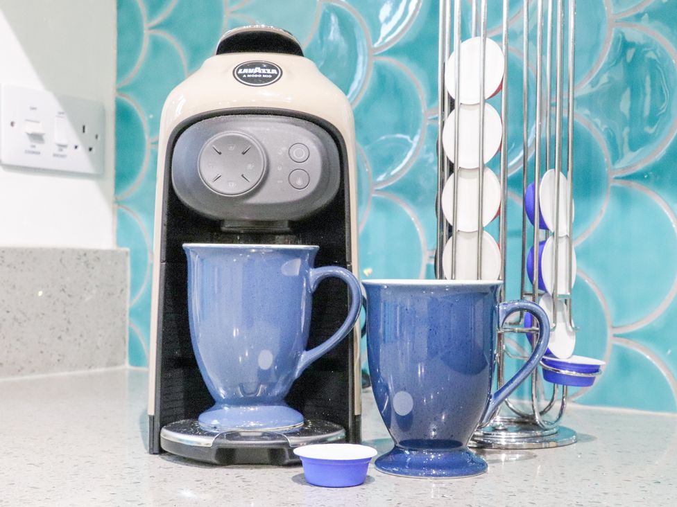 A coffee machine with blue mugs and coffee pods on a kitchen counter at Splatt Barn in Rock
