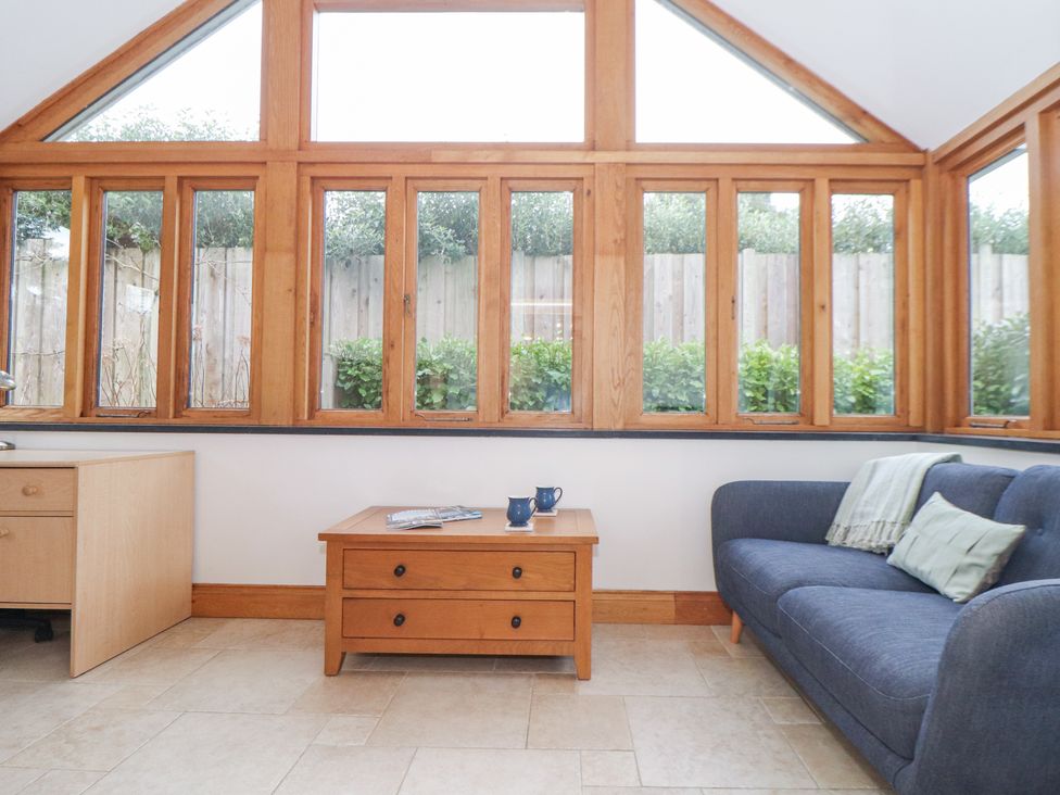 A room with a blue sofa, wooden coffee table, wooden desk, and windows with wooden frames at Splatt Barn in Rock