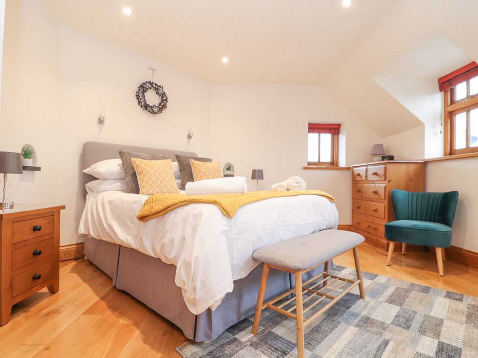 A bedroom with a bed a wooden dresser a green chair and a wooden bench at Splatt Barn in Rock