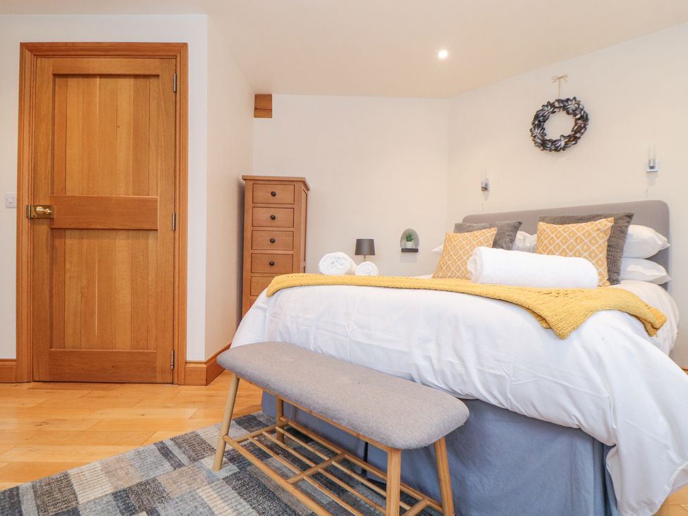 A bedroom with a wooden door a bed with yellow pillows and a bench at Splatt Barn in Rock