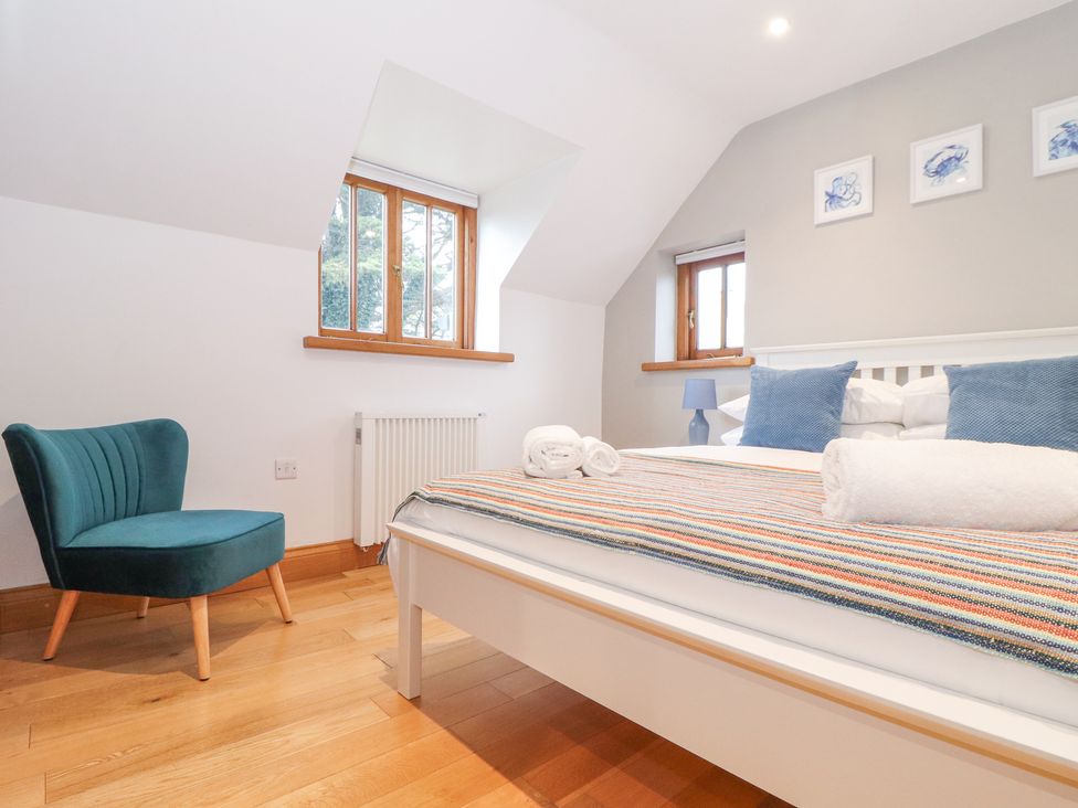 A bedroom with a white bed a blue chair blue pillows and windows at Splatt Barn in Rock