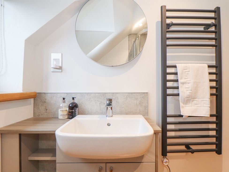 A bathroom sink with soap dispensers a round mirror and a towel rack with a towel at Splatt Barn in Rock