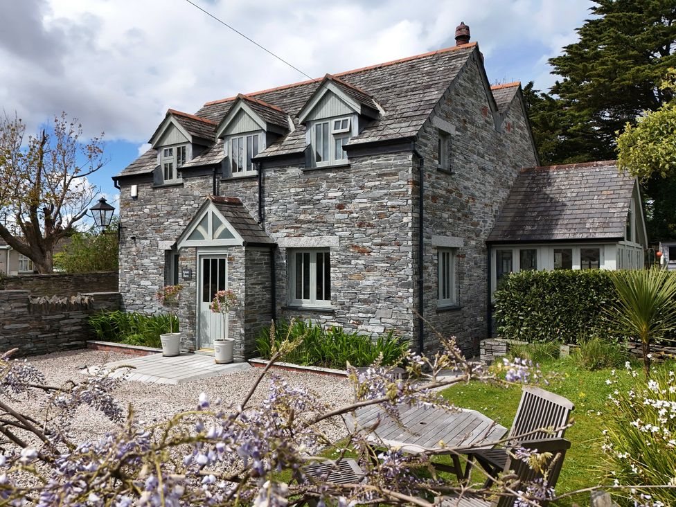 A stone house with dormer windows and a wooden table with chairs in the garden at Splatt Barn in Rock