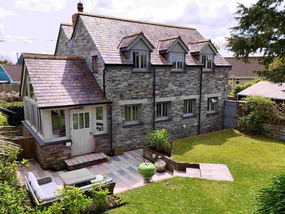 A stone house with multiple windows a patio with outdoor furniture and a green barbecue in a garden at Splatt Barn in Rock