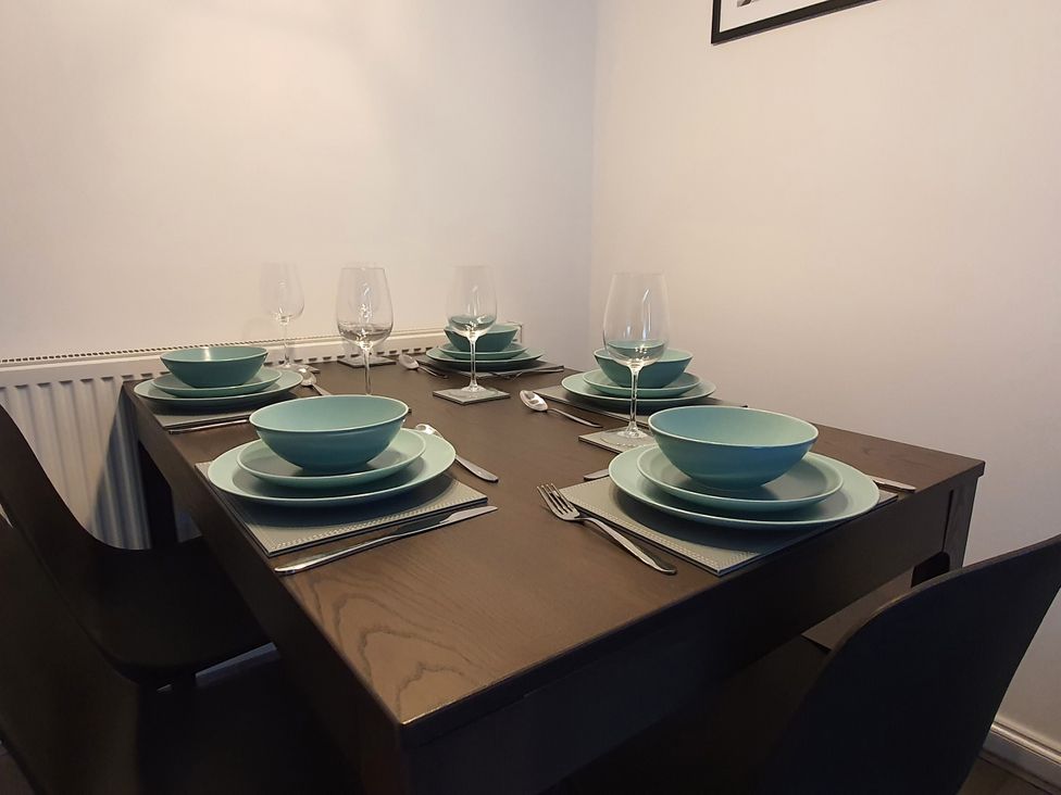 A dining table set with plates, bowls, and glasses at 32 Moorland House