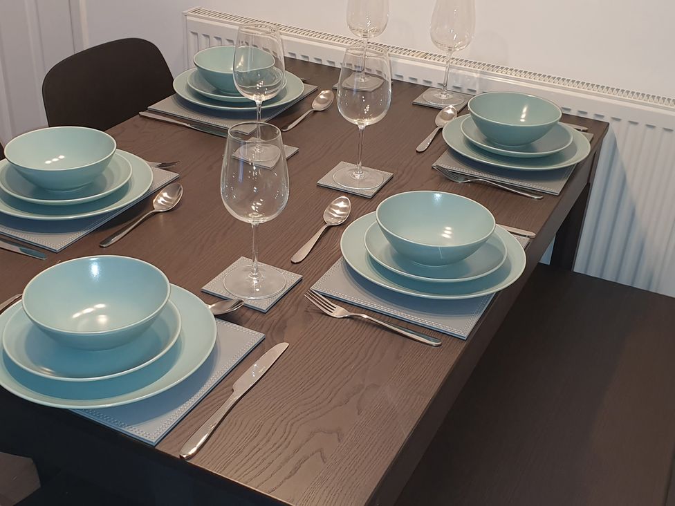 A dining table set with dishes and glasses at 32 Moorland House