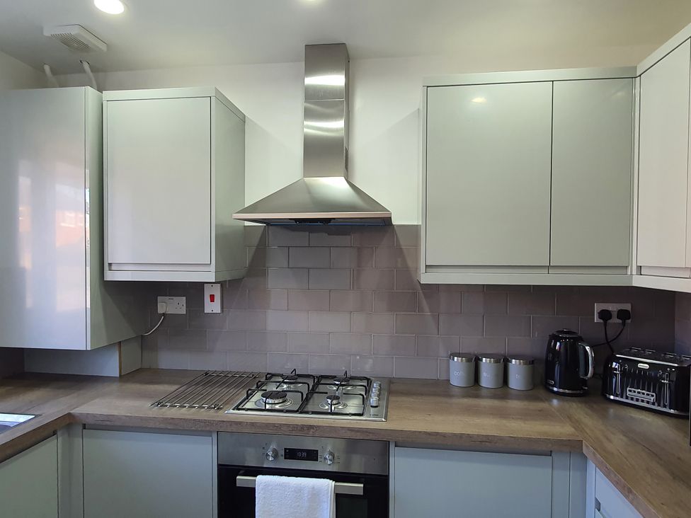 A kitchen with cabinets, gas stove, range hood, kettle and toaster at 32 Moorland House
