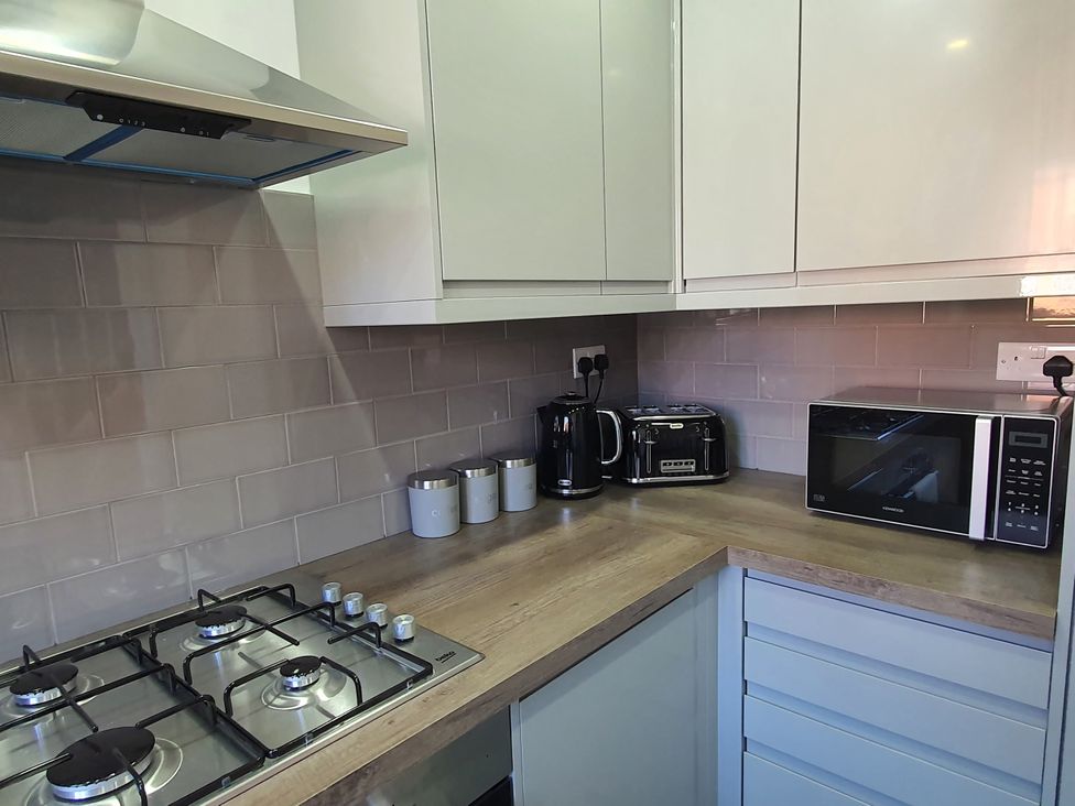 A kitchen with a gas stove and appliances at 32 Moorland House