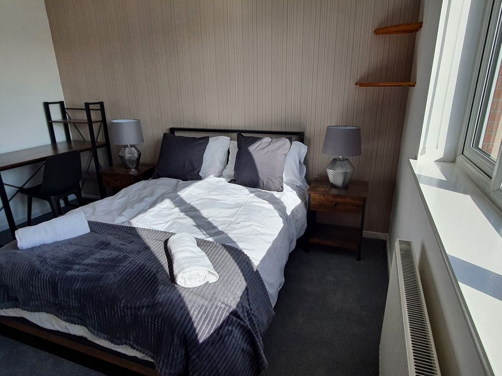 A bedroom with a bed, side tables and a desk at 32 Moorland House