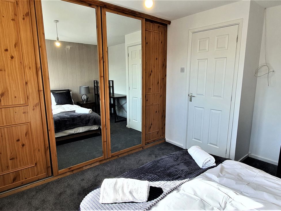 A bedroom with a bed and mirrored wardrobe at 32 Moorland House