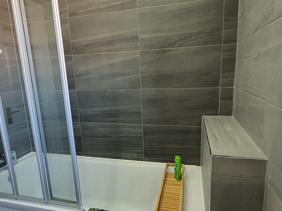 A bathroom with a bathtub and shower doors at 32 Moorland House 