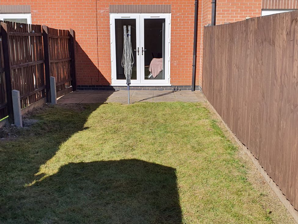 A garden with grass and double doors at 32 Moorland House