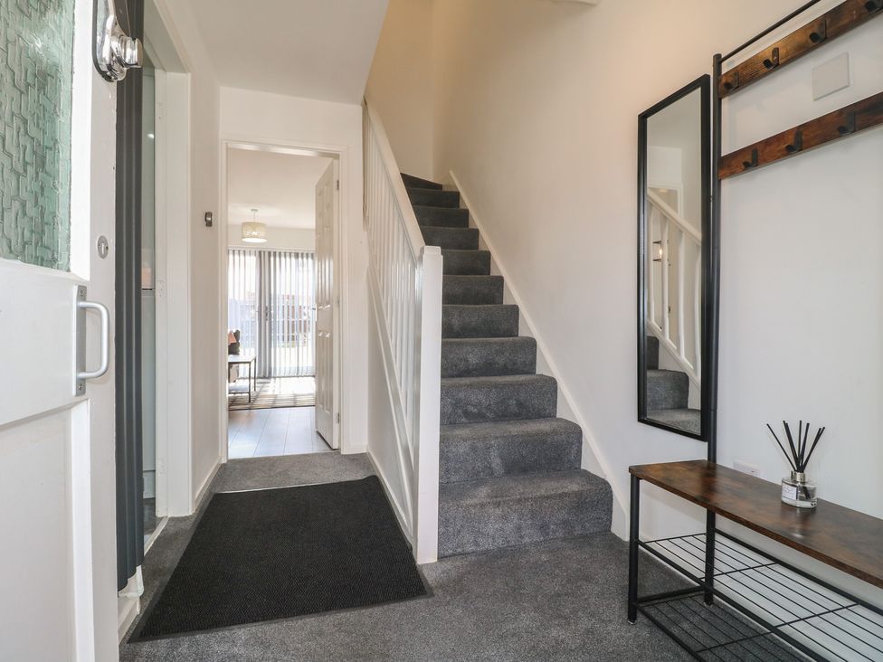 A hallway with stairs and a console table at 32 Moorland House in Syston