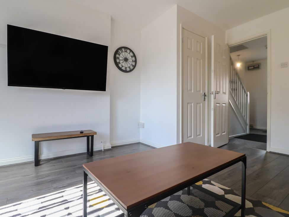 A living room with a television and clock at 32 Moorland House Syston