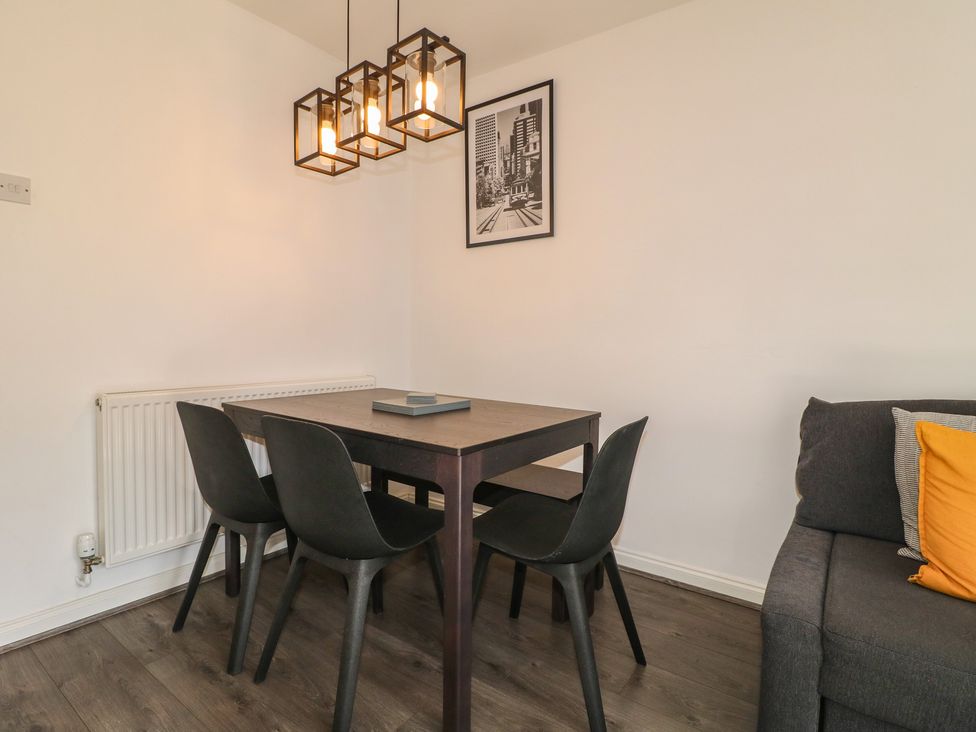 A dining room with a table, chairs, and a sofa at 32 Moorland House Syston