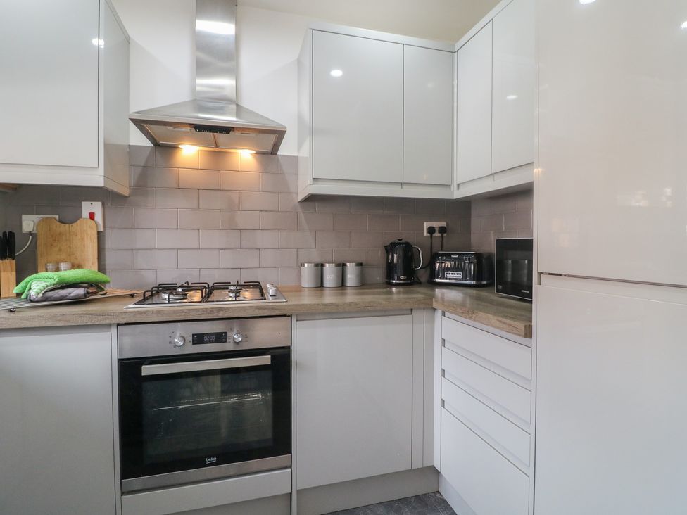 A kitchen with a stove, oven, and various appliances at 32 Moorland House in Syston