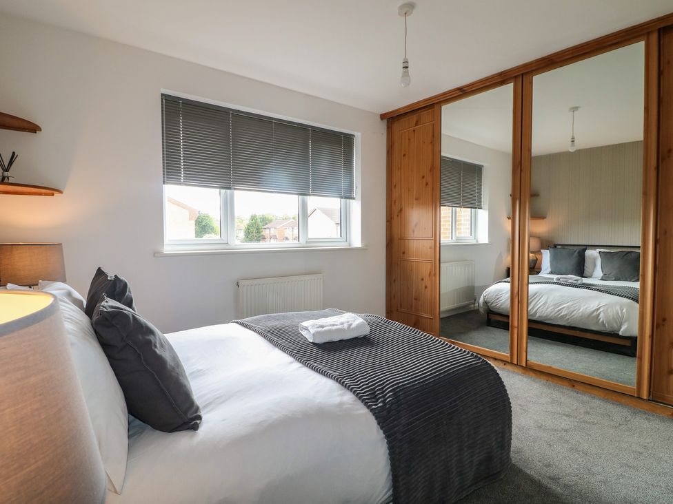 A bedroom with a bed and mirror at 32 Moorland House in Syston