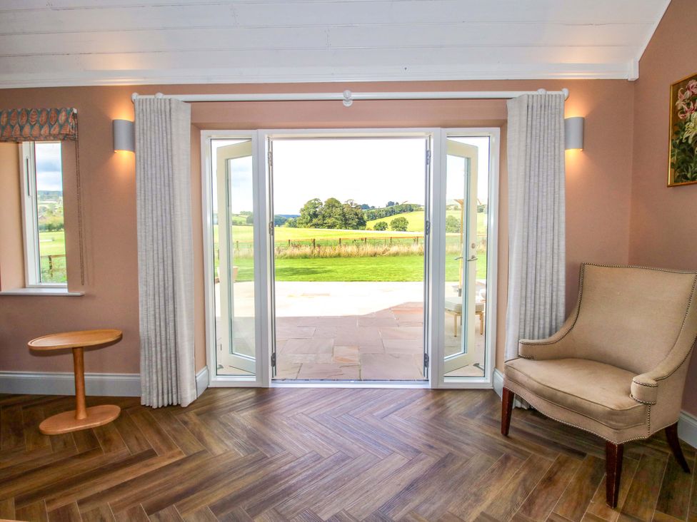 A living room with a chair and table looking out to the garden at Hoddell Pitch Cottage Kinnerton near New Radnor