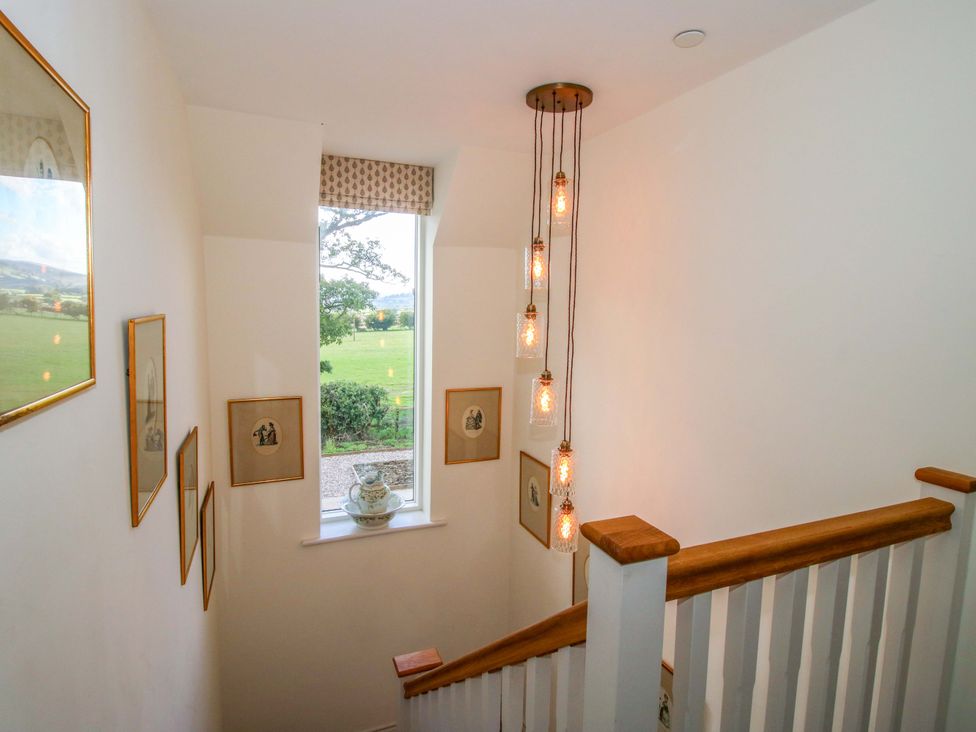 A staircase with light fixtures and framed pictures at Hoddell Pitch Cottage in Kinnerton near New Radnor