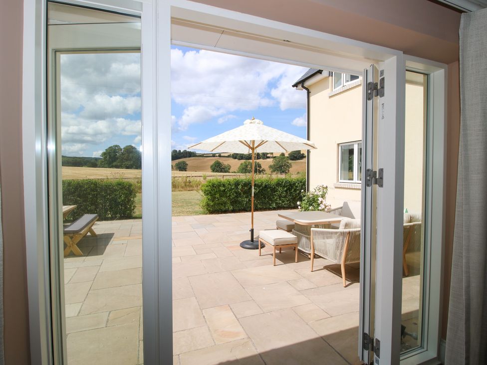 A patio area with seating and a parasol at Hoddell Pitch Cottage Kinnerton near New Radnor