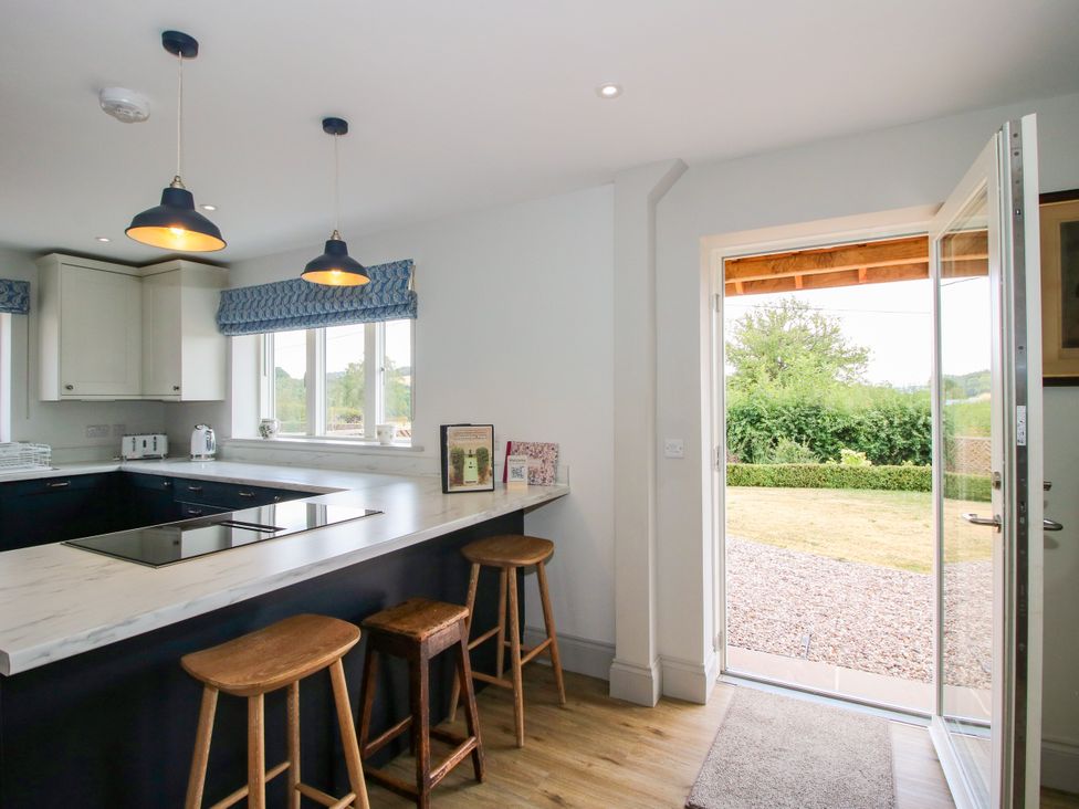 A kitchen with a marble countertop and bar stools at Hoddell Pitch Cottage Kinnerton near New Radnor