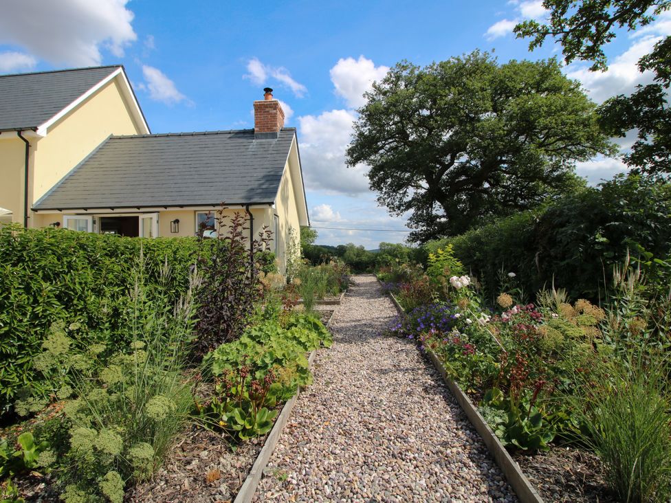 A garden with a pathway lined with flowers at Hoddell Pitch Cottage in Kinnerton near New Radnor
