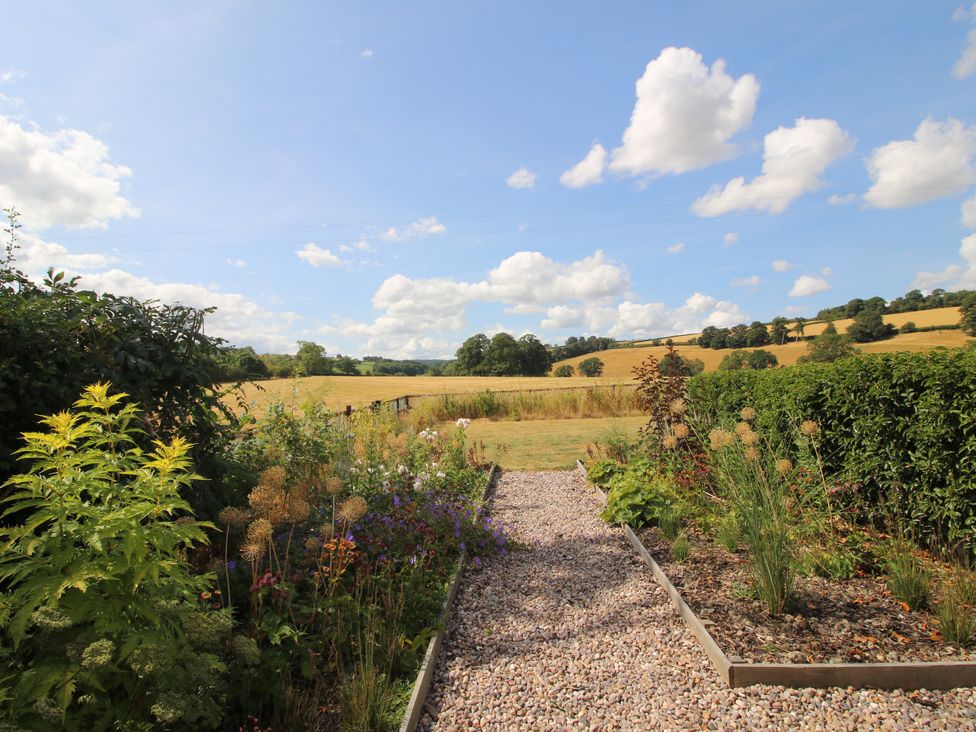 A garden with a gravel path leading to an open field at Hoddell Pitch Cottage Kinnerton near New Radnor