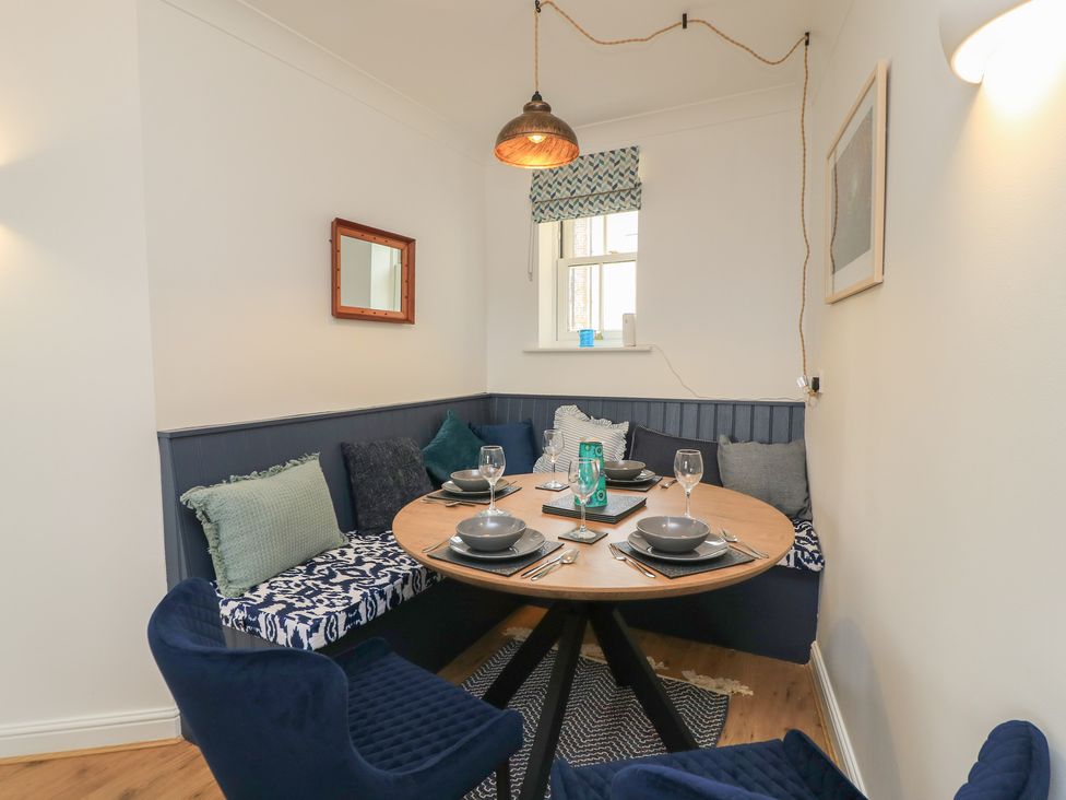 A dining room with a round table and seating at Weyside in Weymouth